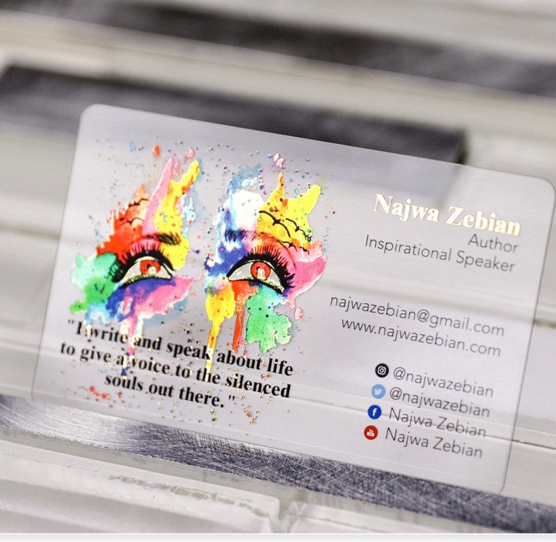 K&ouml;nnte beinhalten: Eine transparente Visitenkarte mit einem farbenfrohen abstrakten Design, das zwei Augen zeigt. Der Text auf der Karte lautet "Najwa Zebian, Autorin, Inspirationsrednerin, najwazebian@gmail.com, www.najwazebian.com, @najwazebian, @najwazebian, Najwa Zebian, Najwa Zebian".