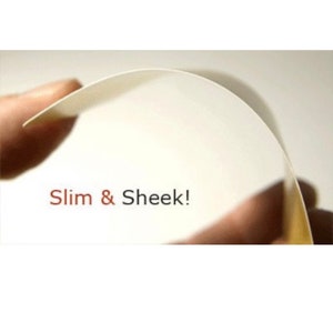 K&ouml;nnte beinhalten: Nahaufnahme einer wei&szlig;en, flexiblen Materialfolie, die in einer Hand gehalten wird. Der Text "Slim & Sheek!" ist in Rot auf die Folie gedruckt.