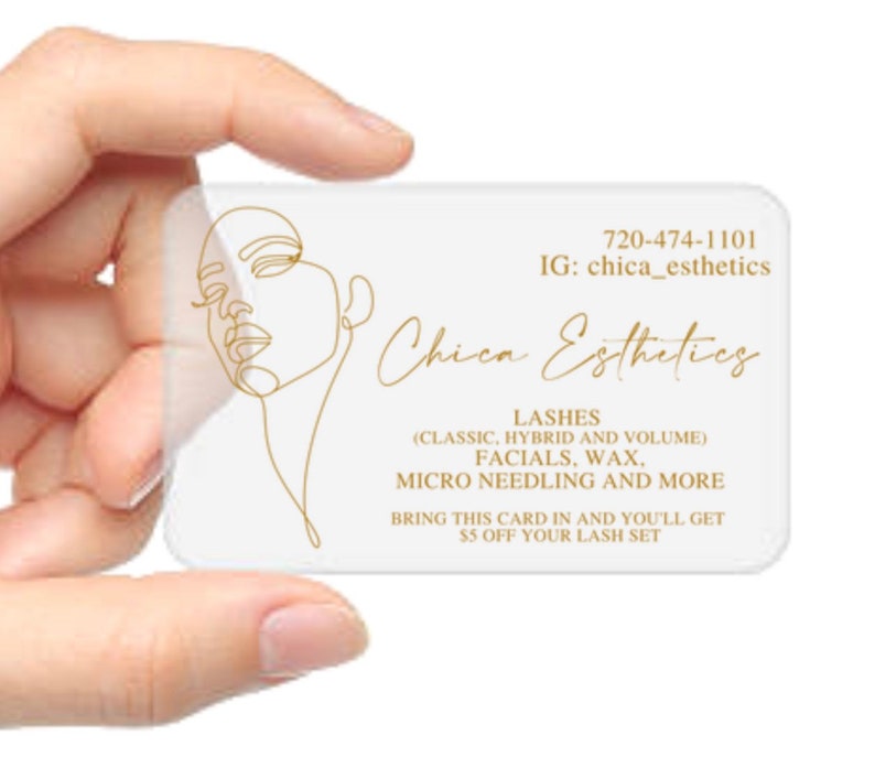 K&ouml;nnte beinhalten: Eine wei&szlig;e Visitenkarte mit goldener Schrift und einer goldenen Linienzeichnung eines Gesichts. Der Text lautet "Chica Esthetics", "720-474-1101", "IG: chica_esthetics", "LASHES (CLASSIC, HYBRID AND VOLUME)", "FACIALS, WAX, MICRO NEEDLING AND MORE", "BRING THIS CARD IN AND YOU'LL GET &euro;5 OFF YOUR LASH SET".