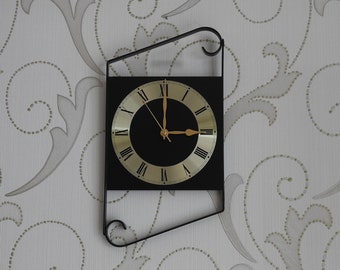 Reloj de pared pequeño hecho a mano de metal con volutas negras