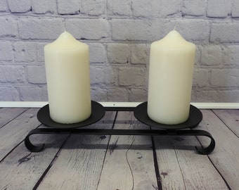 Candelabro doble negro de metal negro, sencillo y hecho a mano, con detalles ornamentales, para velas cilíndricas grandes.