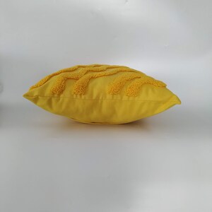 May include: A yellow throw pillow with a textured design. The pillow is made of a soft, plush fabric.