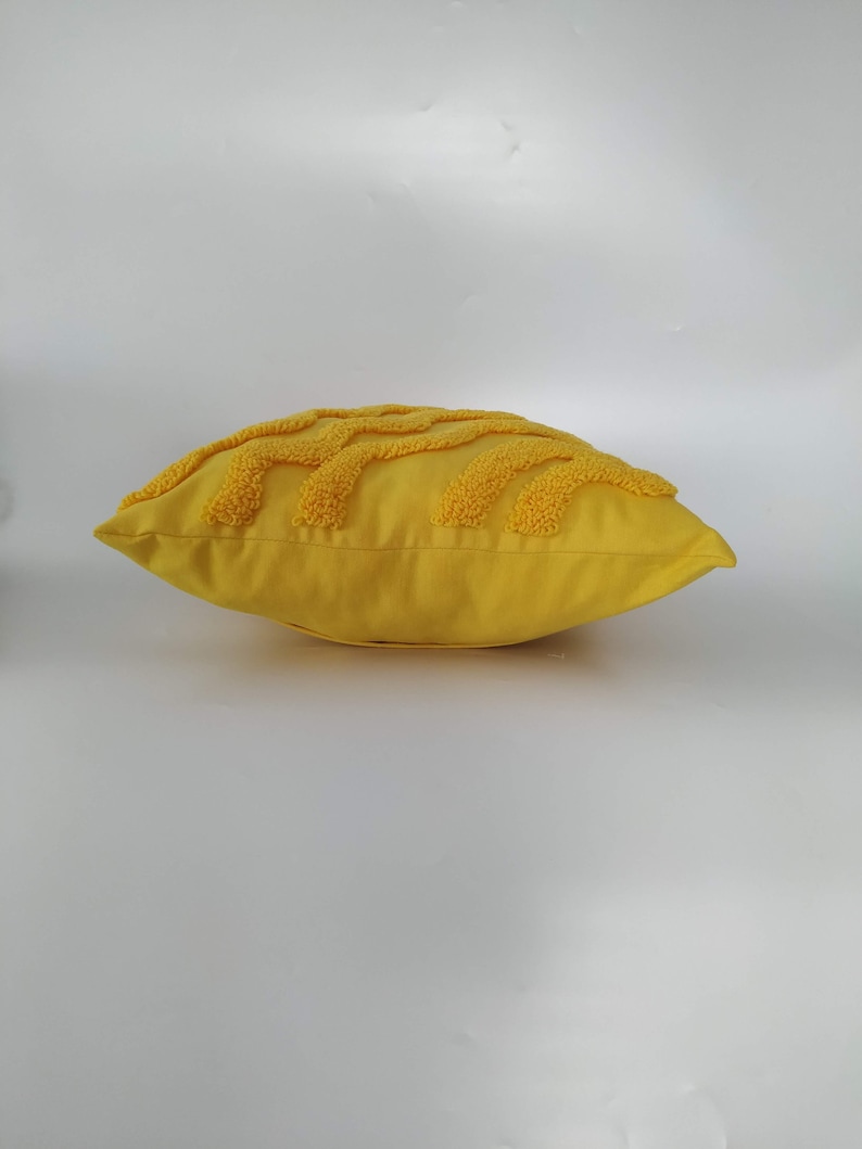 May include: A yellow throw pillow with a textured design. The pillow is made of a soft, plush fabric.