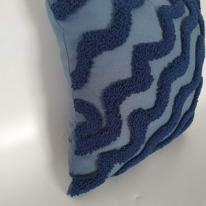 May include: A blue throw pillow with a textured, wavy pattern in a darker shade of blue.