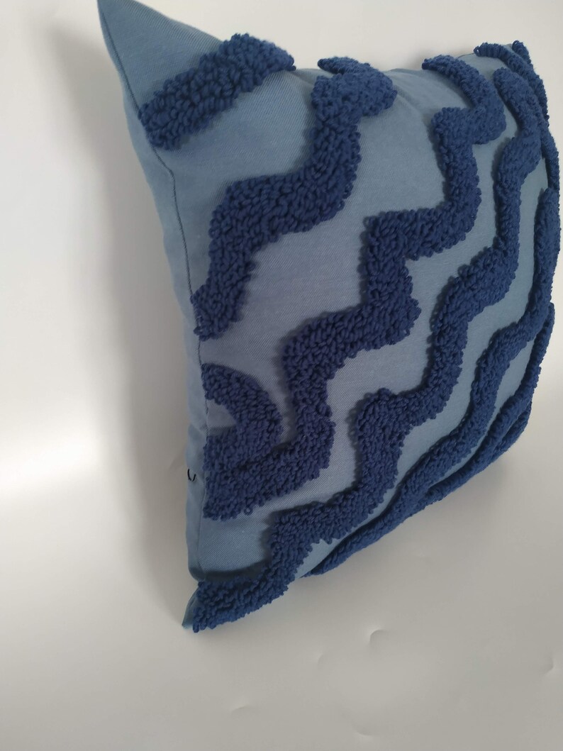 May include: A blue throw pillow with a textured, wavy pattern in a darker shade of blue.
