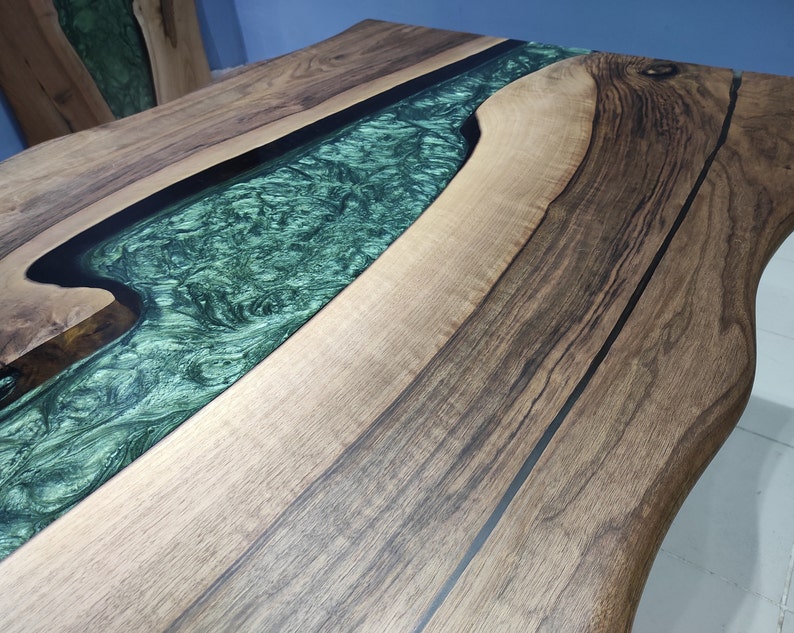 May include: A wooden table top with a green epoxy river running through it. The wood is a dark brown with black lines running through it.