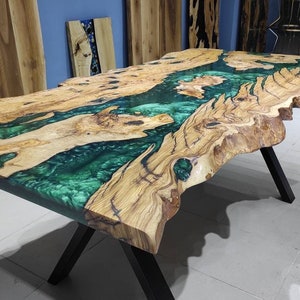 May include: A large wooden table with a live edge top and a green epoxy resin inlay. The table has a black X-shaped base.