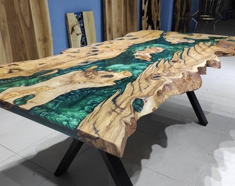 Può includere: Un grande tavolo in legno con un piano a bordo vivo e un'intarsio in resina epossidica verde. Il tavolo ha una base a forma di X nera.