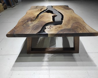 Può includere: Un tavolino da caffè in legno con un piano a bordo vivo e un fiume di resina epossidica nera che attraversa il centro. Il tavolo ha una base semplice e rettangolare.