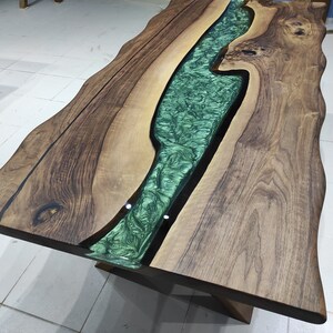 May include: A wooden table with a live edge and a green epoxy river running through the center.