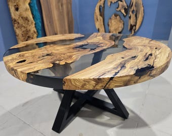 Könnte beinhalten: Runder Couchtisch aus Holz mit einem Design mit lebendiger Kante. Die Tischplatte hat klares Epoxidharz, das die natürlichen Hohlräume im Holz ausfüllt. Der Tisch hat ein schwarzes Metallgestell. Der Tisch hat einen Durchmesser von ca. 91 cm.