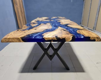 Pode incluir: Mesa de madeira artesanal com um design único. O tampo apresenta um grão de madeira natural com um rio de resina azul no centro. A mesa é suportada por pernas de metal preto.