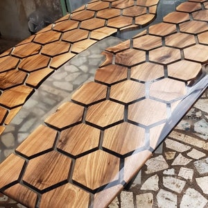 Puede incluir: Una mesa de madera con una incrustaci&oacute;n de resina epoxi transparente. La madera es de color marr&oacute;n oscuro y tiene un patr&oacute;n de panal. La resina epoxi es transparente y tiene una superficie lisa.