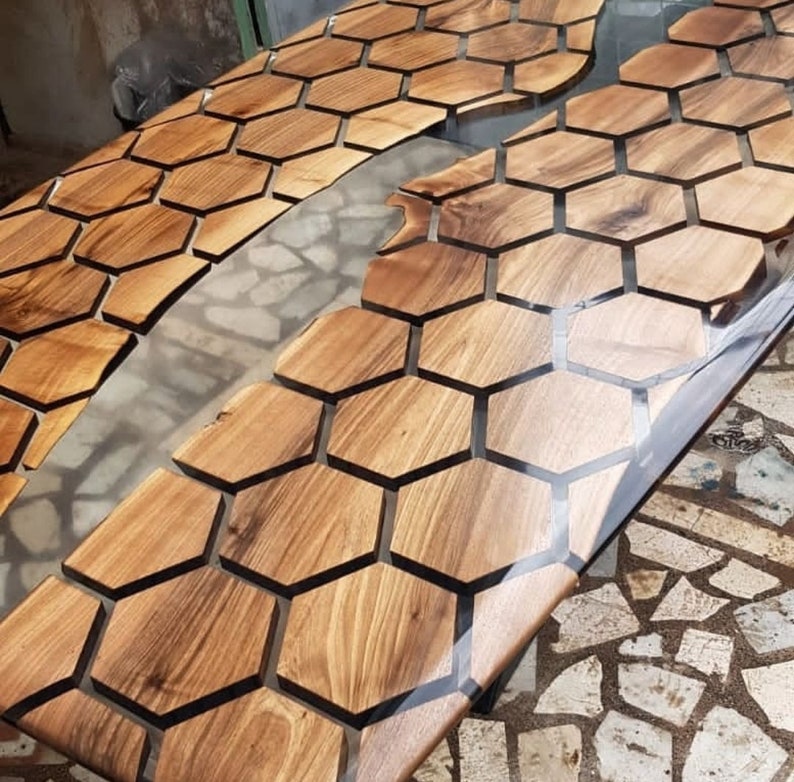 Puede incluir: Una mesa de madera con una incrustaci&oacute;n de resina epoxi transparente. La madera es de color marr&oacute;n oscuro y tiene un patr&oacute;n de panal. La resina epoxi es transparente y tiene una superficie lisa.