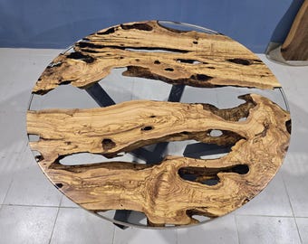Könnte beinhalten: Runder Holztisch mit einer transparenten Epoxidharzmitte. Der Tisch hat ein natürliches Holzmaserungsmuster in Hellbraun und ein dunkelgraues Metallgestell. Der Durchmesser des Tisches beträgt ca. 122 cm.