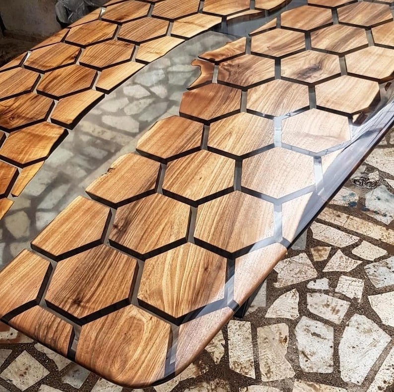 Puede incluir: Una tapa de mesa de madera con un patr&oacute;n de panal de abeja incrustado con resina epoxi transparente. La resina crea un dise&ntilde;o de r&iacute;o a trav&eacute;s del centro de la mesa.