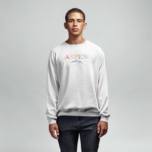 May include: A light gray sweatshirt with a colorful graphic print that says "ASPEN" with a mountain range design underneath.