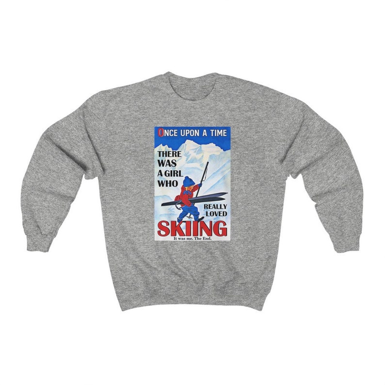 Pode incluir: Uma camisa de frio cinza com uma ilustra&ccedil;&atilde;o vintage de uma menina esquiando. A ilustra&ccedil;&atilde;o inclui o texto "Once Upon A Time There Was A Girl Who Really Loved Skiing. It was me. The End."