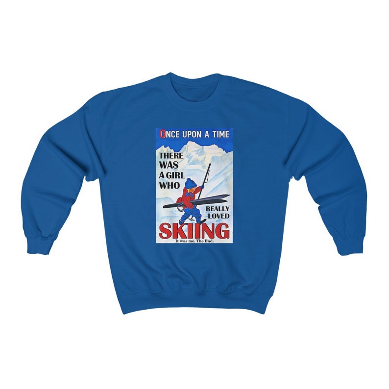 Pode incluir: Uma camisa de frio azul com uma ilustra&ccedil;&atilde;o vintage de uma menina esquiando. O texto diz "Era uma vez uma menina que realmente amava esquiar. Era eu. Fim."