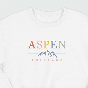 May include: White sweatshirt with a colorful graphic design that says "ASPEN COLORADO" with a stylized mountain range in blue.