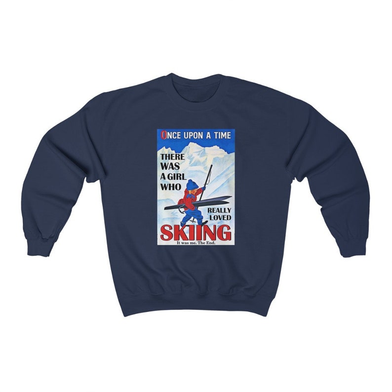 Pode incluir: Uma camisa de frio azul marinho com uma ilustra&ccedil;&atilde;o vintage de uma menina esquiando. A ilustra&ccedil;&atilde;o inclui o texto "Once Upon A Time There Was A Girl Who Really Loved Skiing. It was me. The End."