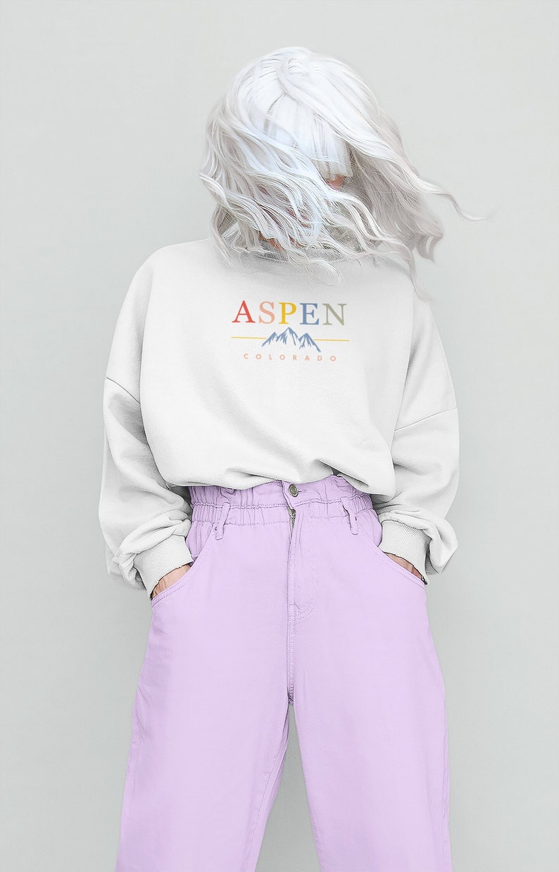 May include: A white sweatshirt with the text "ASPEN COLORADO" and a graphic of mountains in colorful hues.