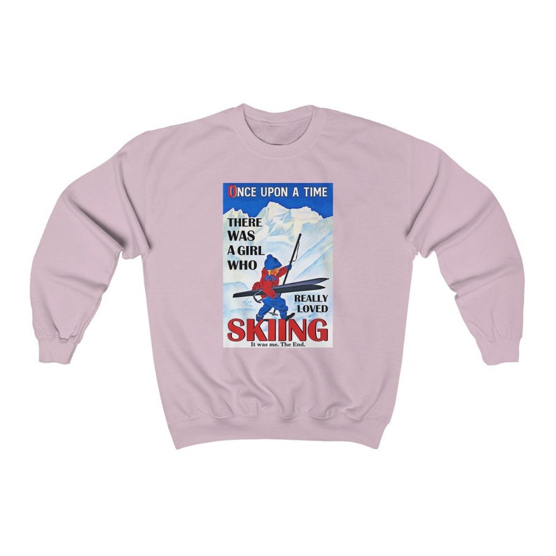 Pode incluir: Uma camisa de frio rosa claro com uma ilustra&ccedil;&atilde;o vintage de uma menina esquiando. O texto diz "Era uma vez, havia uma menina que realmente amava esquiar. Era eu. Fim."