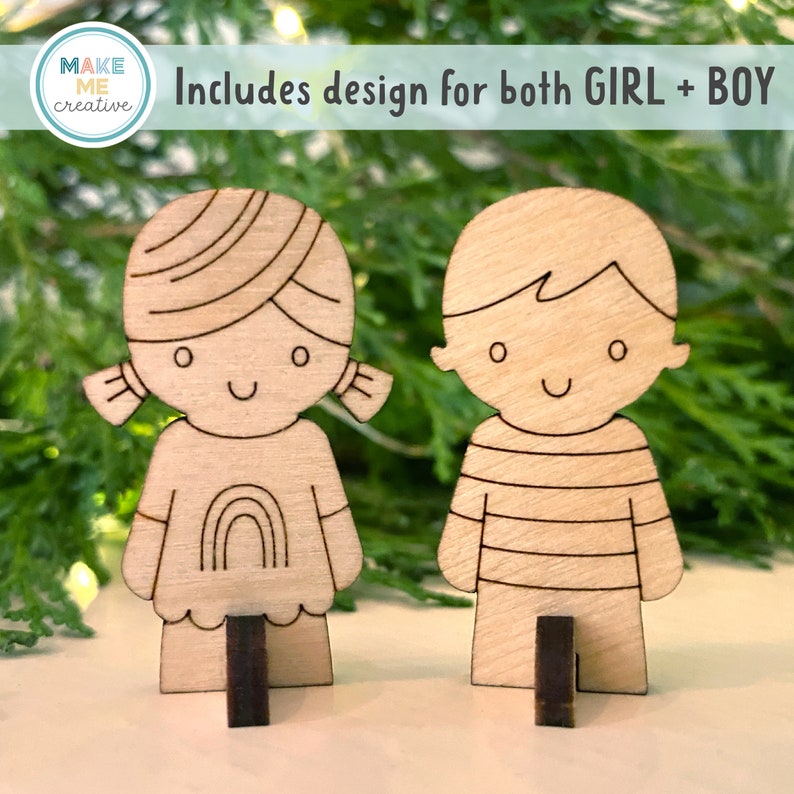 May include: Two wooden cutout figures of a girl and a boy, both with smiling faces. The girl has a rainbow on her shirt and the boy has a striped shirt. The figures are standing on small wooden bases. The text "Includes design for both GIRL + BOY" is visible above the figures.