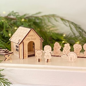 May include: A wooden playset with a house, a girl, a bear, and flowers. The house has a sign that says "Ronnie's Little House".