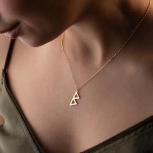 May include: A gold necklace with a geometric triangle pendant. The pendant is made of two overlapping triangles.