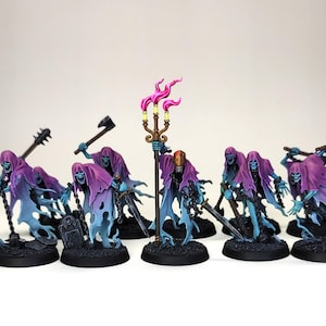 May include: A collection of miniature fantasy figures. Each figure is a spectral warrior with a purple hooded cloak, blue ethereal body, and various weapons. One figure holds a staff with pink flames.
