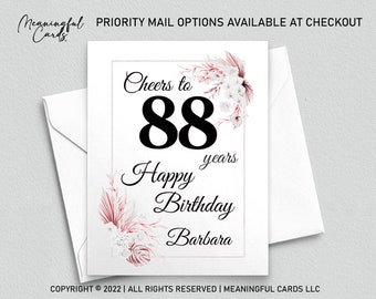 May include: A white card with pink floral designs and the text "Cheers to 88 years Happy Birthday Barbara".