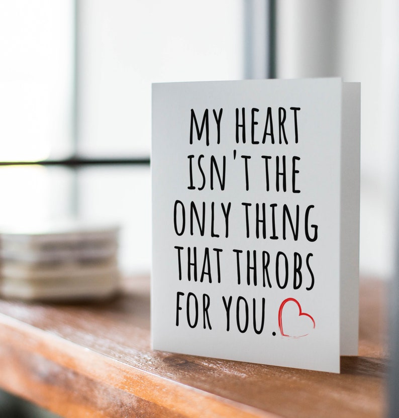 Puede incluir: Tarjeta blanca con texto negro que dice "Mi coraz&oacute;n no es lo &uacute;nico que late por ti." Un coraz&oacute;n rojo est&aacute; dibujado al lado del texto.