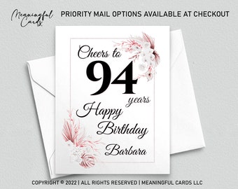 May include: A white card with a floral design in shades of pink and white. The card says "Cheers to 94 years Happy Birthday Barbara".