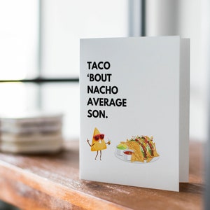 May include: A white greeting card with the text "TACO 'BOUT NACHO AVERAGE SON." features a cartoon nacho chip wearing sunglasses and holding a drink. A plate of nachos with salsa and guacamole is also illustrated.