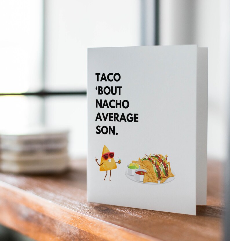 May include: A white greeting card with the text "TACO 'BOUT NACHO AVERAGE SON." features a cartoon nacho chip wearing sunglasses and holding a drink. A plate of nachos with salsa and guacamole is also illustrated.