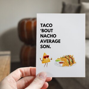 May include: A white greeting card with the text "TACO 'BOUT NACHO AVERAGE SON." features a cartoon nacho chip wearing sunglasses and holding a drink. A plate of tacos and nachos is also shown.
