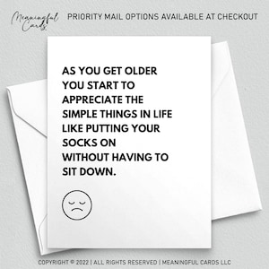 May include: A white greeting card with a humorous message about aging. The text reads, "AS YOU GET OLDER YOU START TO APPRECIATE THE SIMPLE THINGS IN LIFE LIKE PUTTING YOUR SOCKS ON WITHOUT HAVING TO SIT DOWN." A sad face is at the bottom.