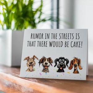 May include: A white card with the text "RUMOR IN THE STREETS IS THAT THERE WOULD BE CAKE!" and four cartoon dogs with different expressions. The dogs are wearing party hats and there are confetti and streamers around them.