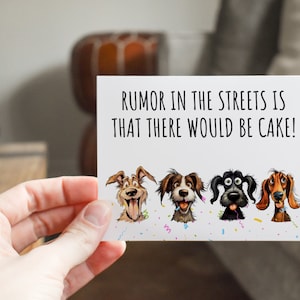 May include: A white card with the text "RUMOR IN THE STREETS IS THAT THERE WOULD BE CAKE!" and four cartoon dogs with different expressions. The dogs are surrounded by confetti.