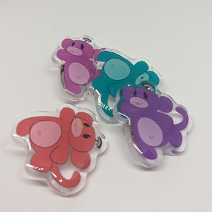 Peut inclure: Quatre épingles de dessin animé d'ours colorés avec un motif arc-en-ciel. Les ours sont rose, bleu, violet et rouge.