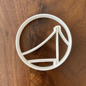 May include: White plastic cookie cutter shaped like a bridge in a circle.