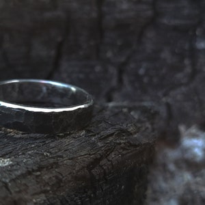 A hand-forged black steel ring with polished edges in a fire pit.