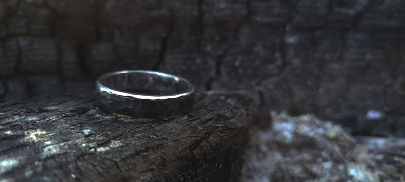 A hand-forged black steel ring with polished edges in a fire pit.