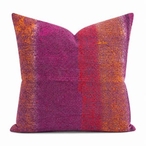 May include: A square throw pillow featuring a textured surface with vertical bands of deep purple, magenta, and vibrant orange. The fabric displays a dense, intricate pattern of small, raised stitches throughout, creating a tactile appearance.