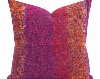 May include: A square throw pillow featuring a textured surface with vertical bands of deep purple, magenta, and vibrant orange. The fabric displays a dense, intricate pattern of small, raised stitches throughout, creating a tactile appearance.