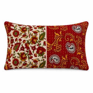 May include: A rectangular throw pillow featuring a split design. The left side has a cream background with red and green floral patterns. The right side is solid red with yellow paisley and vine motifs, accented by visible white running stitch lines.