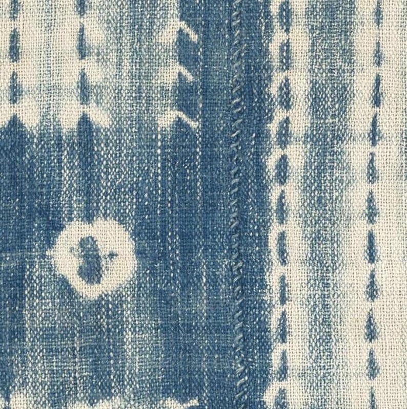 Puede incluir: Un tejido con un patr&oacute;n de te&ntilde;ido anudado en azul profundo y blanco roto. El dise&ntilde;o consiste en rayas verticales, motivos circulares y formas rectangulares creadas mediante una t&eacute;cnica de te&ntilde;ido por reserva sobre una tela de tejido grueso.