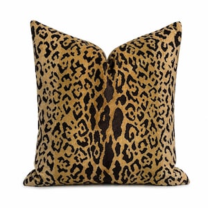 May include: A square throw cushion featuring a prominent black and golden-brown leopard print pattern. The fabric has a textured, velvet-like appearance with a dense, repeating animal spot design covering the entire front surface of the cushion.
