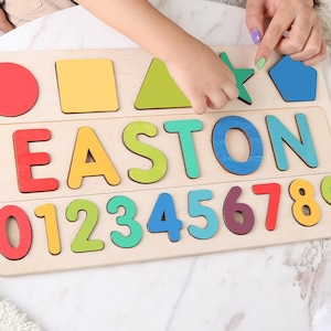 May include: Wooden puzzle board with colorful shapes, letters spelling "EASTON", and numbers 0-9. The shapes include a red circle, yellow square, green triangle, green star, and blue pentagon. A fun educational toy.